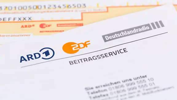 Ein Schreiben vom ARD/ZDF-Beitragsservice liegt auf einem Überweisungsträger.