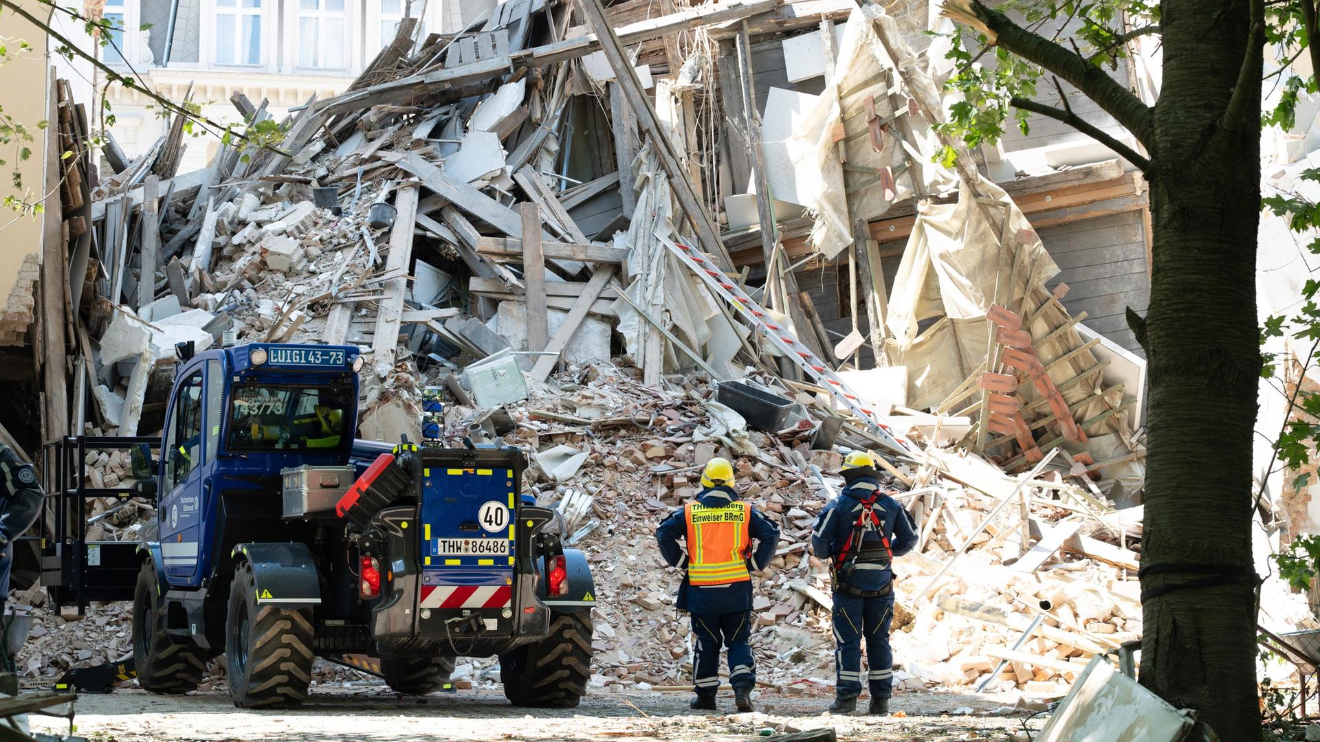EinsatzkrÃ¤fte des Technischen Hilfswerks (THW) stehen vor dem Schuttberg des eingestÃ¼rzten Wohnhauses in der Innenstadt. | picture alliance/dpa | Sebastian Kahnert